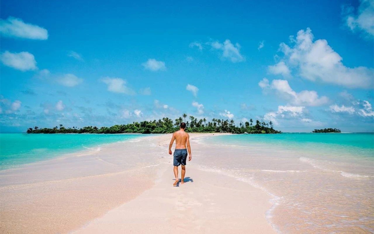 Man walking across a sandbank towards a tropical island in Palau