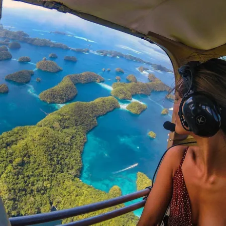 woman in small airplane with open door looking down at the Rock Islands of Palau