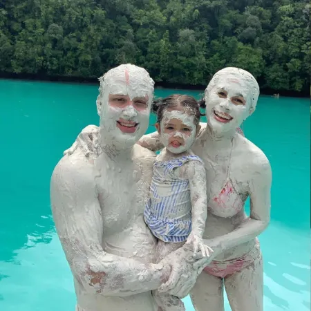 father, mother and small kid covered in mud from Milky Way Bay in Palau