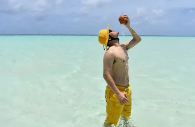 man standing in the ocean in Palau enjoying a coconut drink