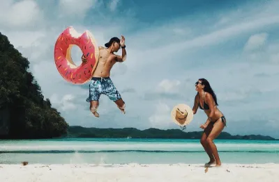 couple at the beach in Palau, guy is jumpingt