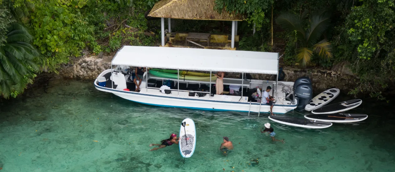 Palau Explorer boat landing at the Stone Money quarry, people in the clear water enjoying paddle boards